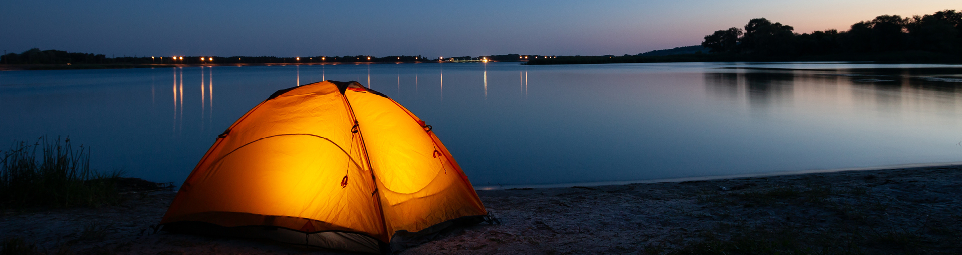 Stimmungsvoll beleuchtetstes Zelt bei Nacht an einem See
