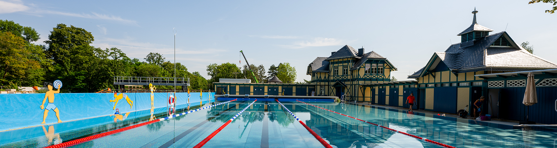 Foto mit Blick über das Becken auf das Gebäude vom Dreienbrunnenbad