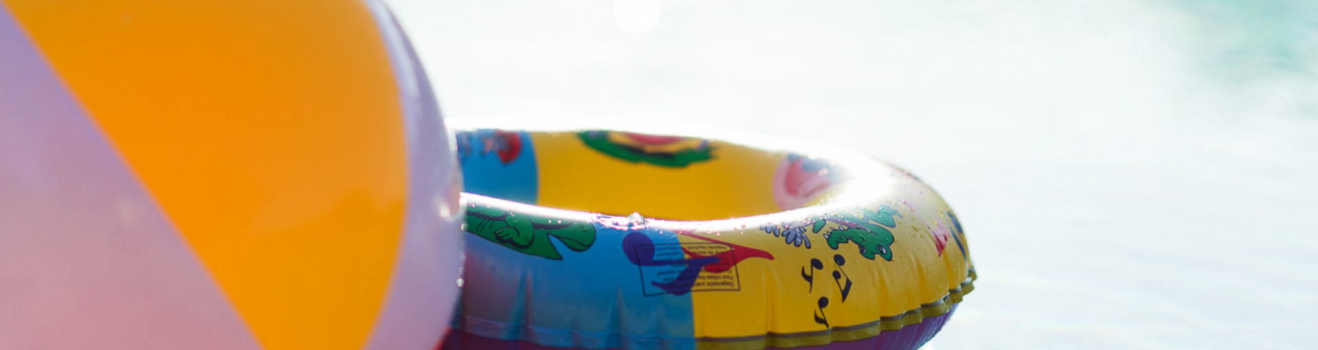 Wasserball und Schwimmring mit Wasser im Hintergrund